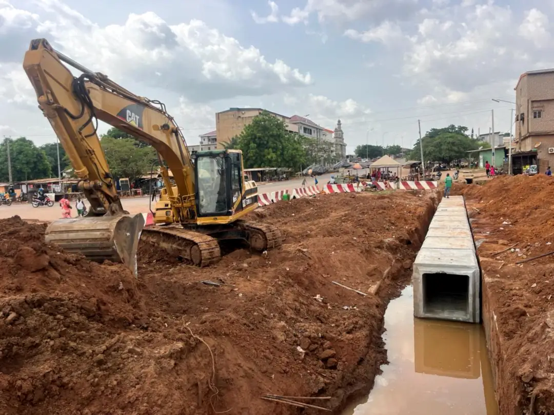 Pose d’un dalot préfabriqué à la pelle mécanique lors de travaux de voirie à Abidjan