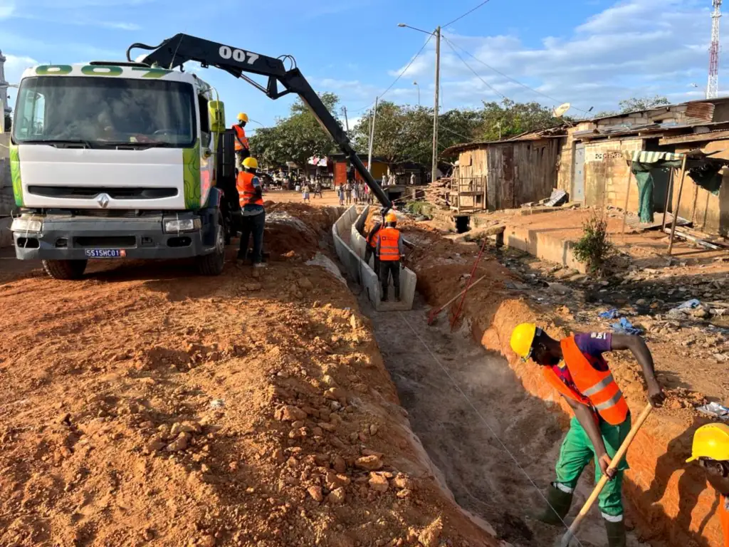 Équipe et camion-grue d’Ets Gana Ousmane posant une canalisation dans une tranchée, quartier d’Abidjan