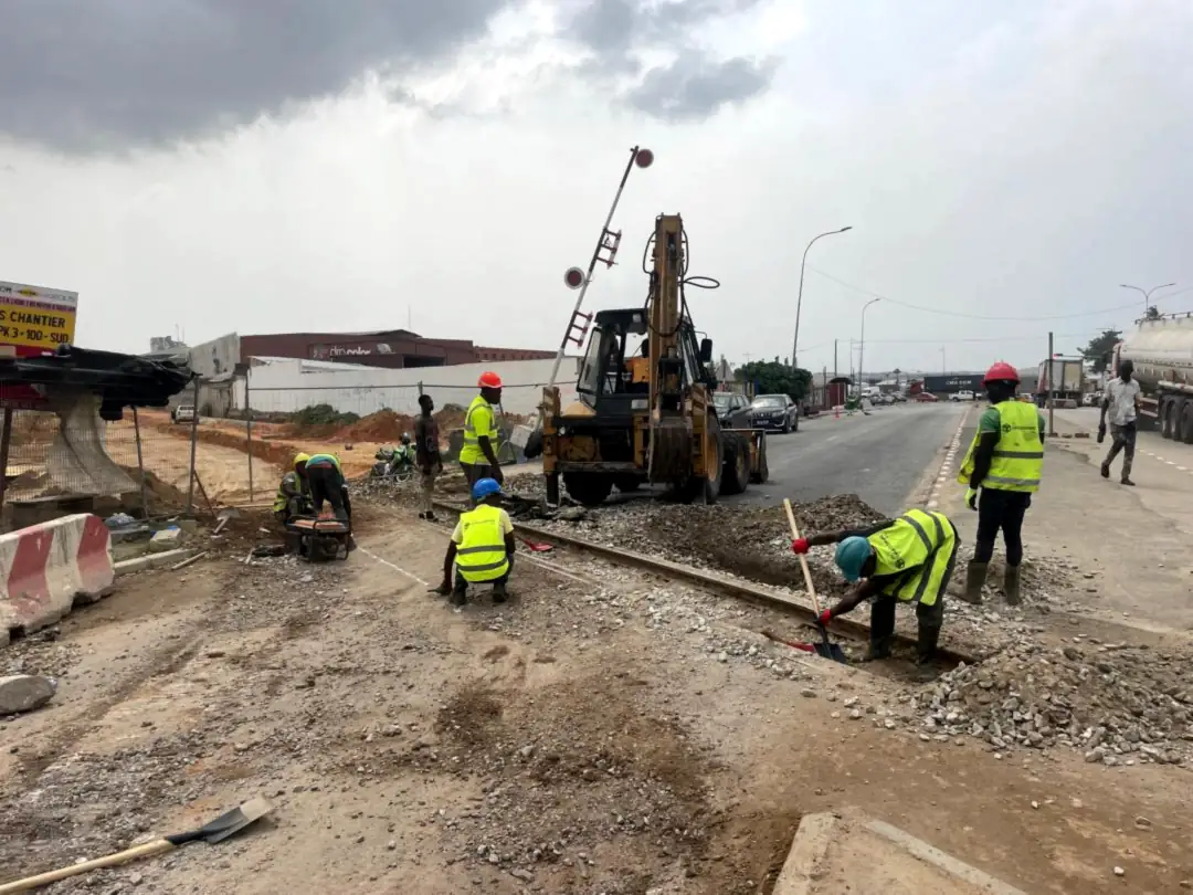Chantier de voirie urbaine avec engins et équipes signalisées à Abidjan